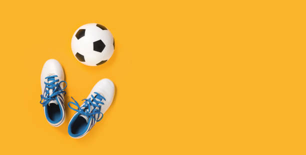 Soccer ball and cleats on bright orange background