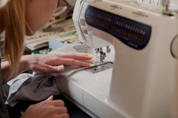 istock woman in glasses sews on modern sewing machine 1235171197