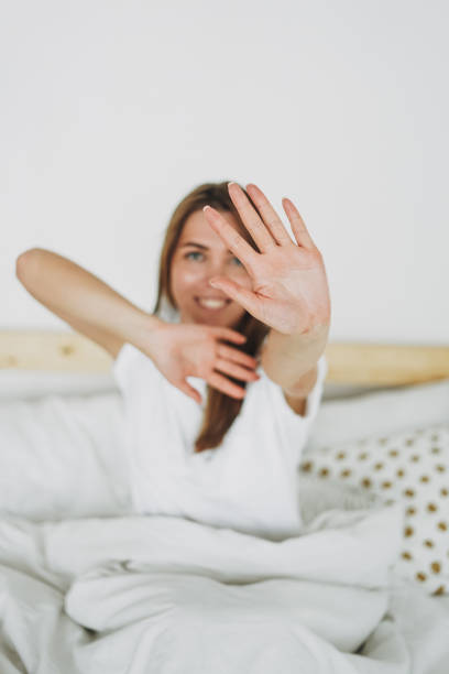 istock Long hair young woman pulling hand towards camera sitting on the bed 1235177422