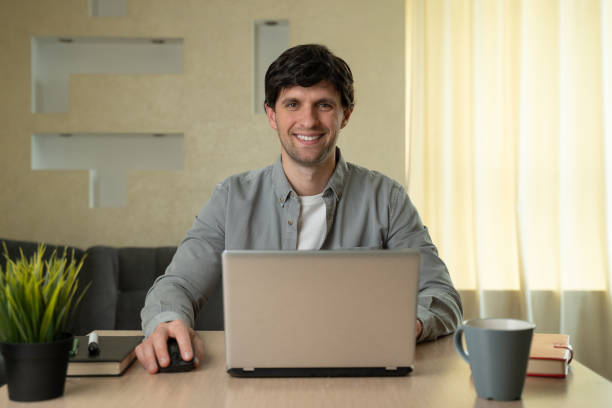 istock Smiling man using laptop studying working online at home 1235185141