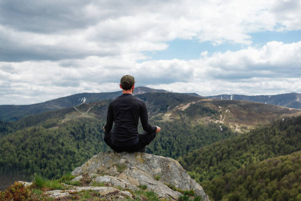 istock Young man meditate at lotus pose in mountains 1235200237