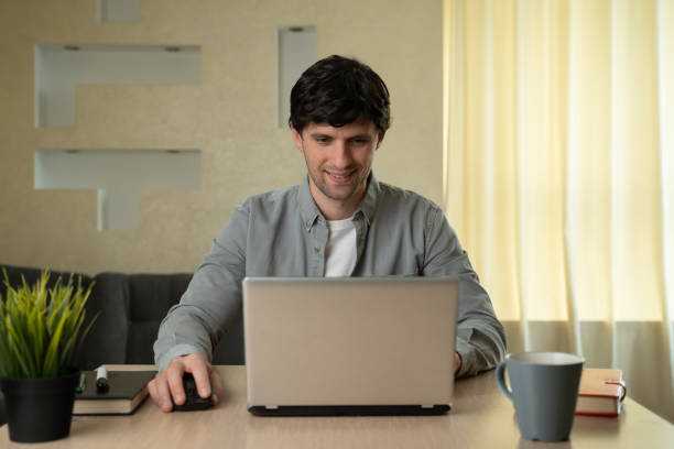 istock Smiling man using laptop studying working online at home 1235208602