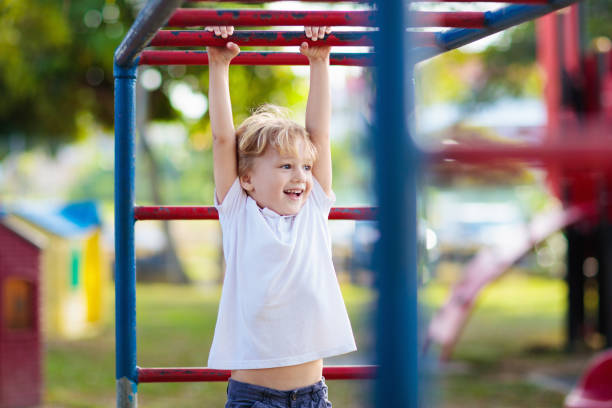 Child on playground. Kids play outdoor. Child playing on outdoor playground in rain. Kids play on school or kindergarten yard. Active kid on colorful monkey bars. Healthy summer activity for children. Little boy climbing. playground stock pictures, royalty-free photos & images