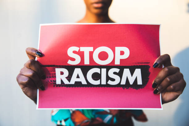 Woman holding a red sign agains racism Woman holding a red sign agains racism racial equality photos stock pictures, royalty-free photos & images