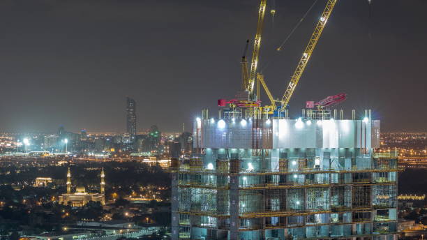 activité de construction dans le centre-ville de dubaï avec des grues et des travailleurs timelapse, émirats arabes unis - night cityscape dubai long exposure photos et images de collection