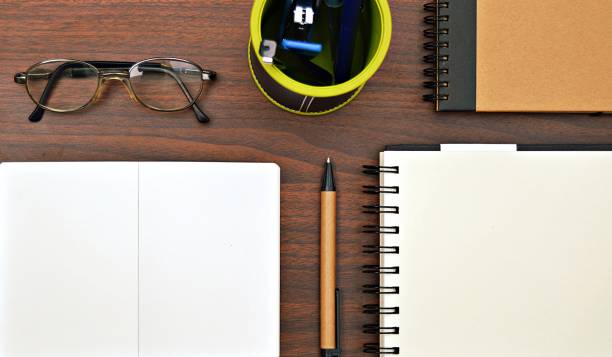 istock Three notepads placed over a wooden brown desk along with stationery items 1235287044