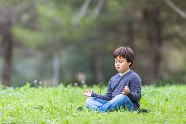 istock Little boy meditating on a green meadow 1235315487