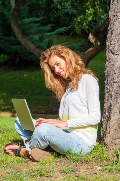 istock Beautiful woman working and typing on laptop keyboard while sitting in the park 1235343821
