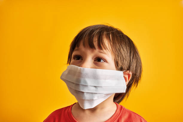 istock Child on yellow background with surgical mask. 1235367910
