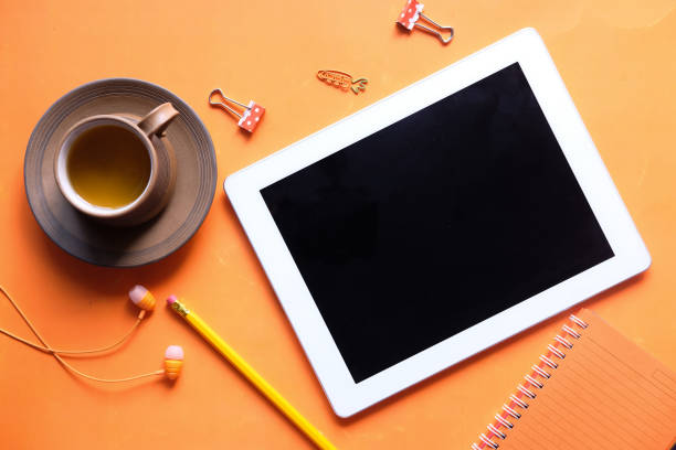 Top view of digital tablet with screen on orange background .