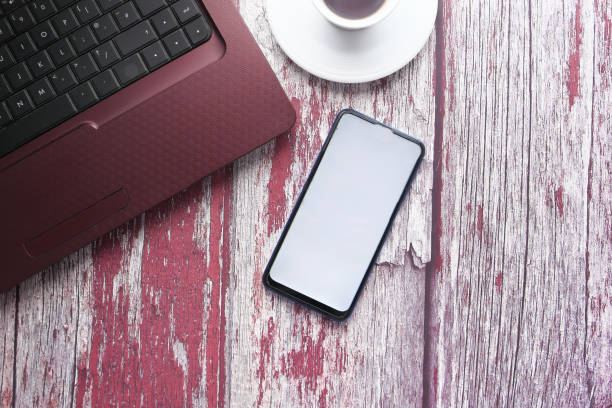 istock smart phone with empty screen and laptop on wooden background 1235382251