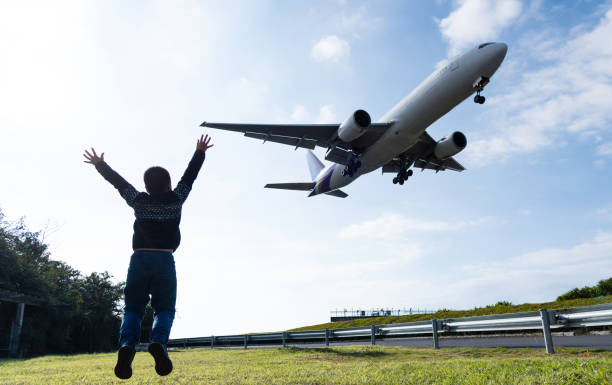 istock Boy arms raised and waving to the airplane 1235390122
