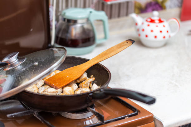 istock fried chicken in a open pan with ground black pepper and wooden kitchen spatula 1235396443