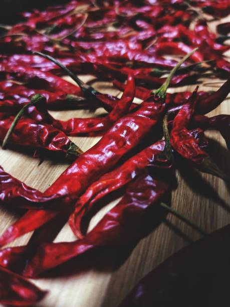Close up shot of red chillies on wooden table captured by mobile phone.