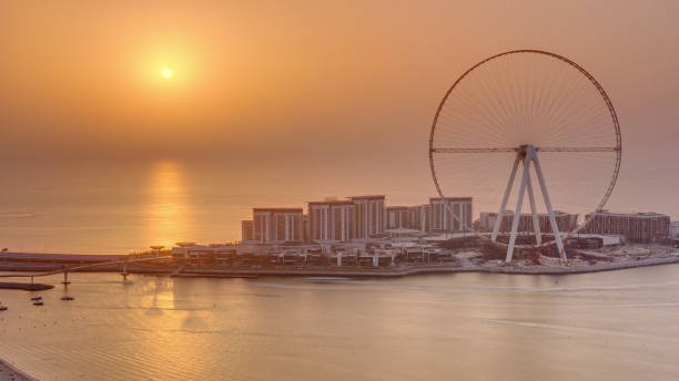 coucher du soleil au-dessus de l’île de bluewaters dans le timelapse aérien de dubaï - ferris wheel wheel blurred motion amusement park photos et images de collection