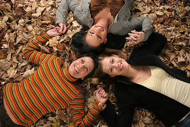 Three girlfriends on the autumn leaves.