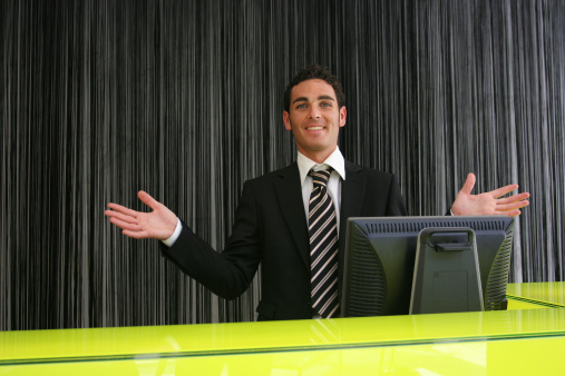 Hotel receptionist with hands in the air.