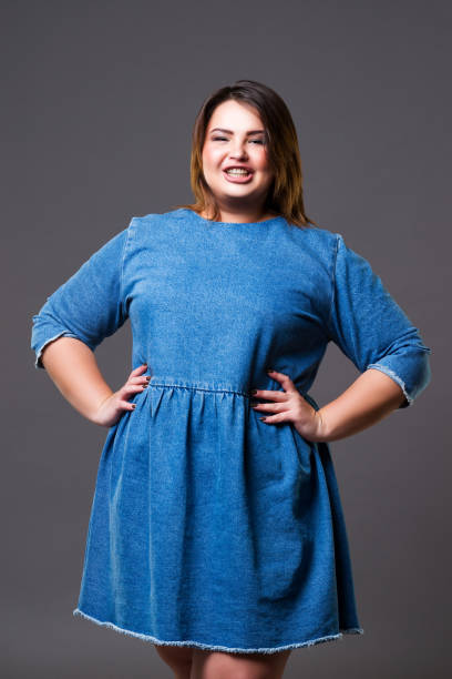 istock Plus size fashion model in a denim dress on gray background 1235545113
