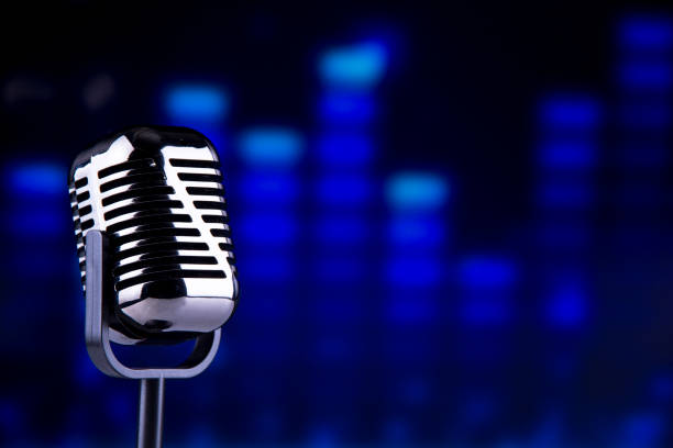 standing microphone head in front of blue led light stock photo