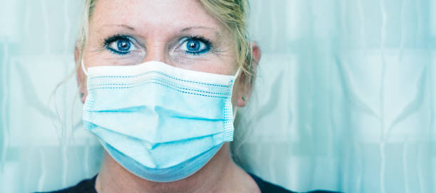 Close up of pretty nurse wearing face mask Portrait of a confident blond nurse wearing a face mask at work during her 12 hour shift during the Covid-19 pandemic, Midwest, USA frontline worker mask stock pictures, royalty-free photos & images