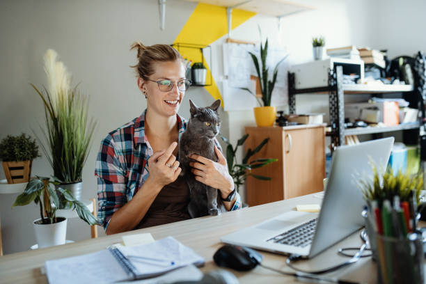 istock Businesswoman using laptop at home for video call and telecommuting, while cuddling her cat 1235597637