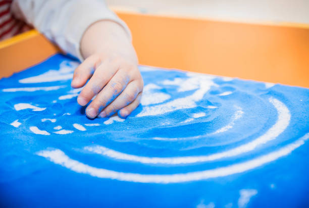 la mano del niño dibuja con arena de color sobre una mesa o tableta - sandbox child human hand sand fotografías e imágenes de stock