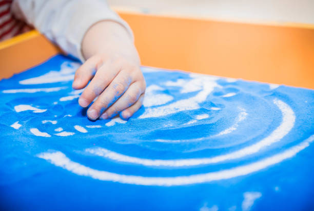 la main de l’enfant dessine avec du sable coloré sur une table ou une tablette - sandbox child human hand sand photos et images de collection