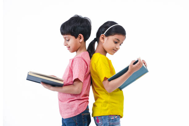 Girl and Boy reading book with back facing each other Indian, Asian Boy and Girl standing and reading book with back facing each other boy and girl reading stock pictures, royalty-free photos & images