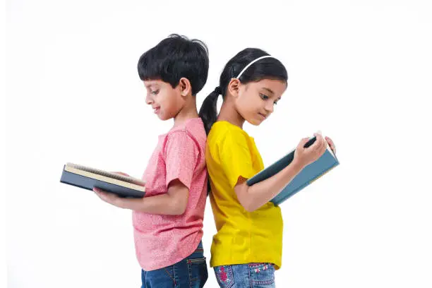 Indian, Asian Boy and Girl standing and reading book with back facing each other