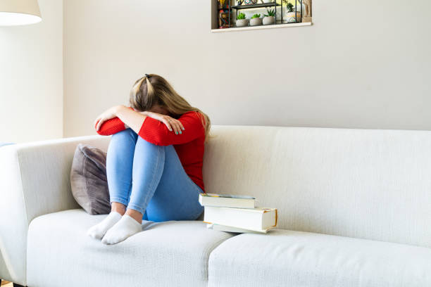 istock Sad young woman sitting on sofa at home 1235612042