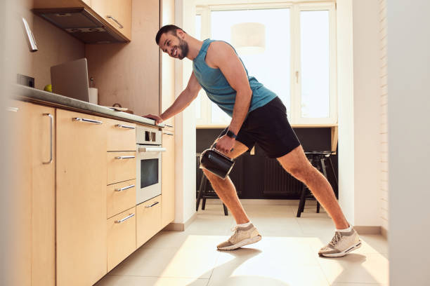 istock Cheerful young man doing exercise with electric kettle 1235614555