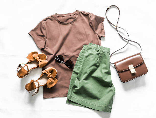 camiseta marrom de verão feminina, shorts verde algodão, sandálias de camur�ça, bolsa de corpo cruzado em um fundo leve, vista para cima. conceito de beleza da moda - belt leather fashion women - fotografias e filmes do acervo