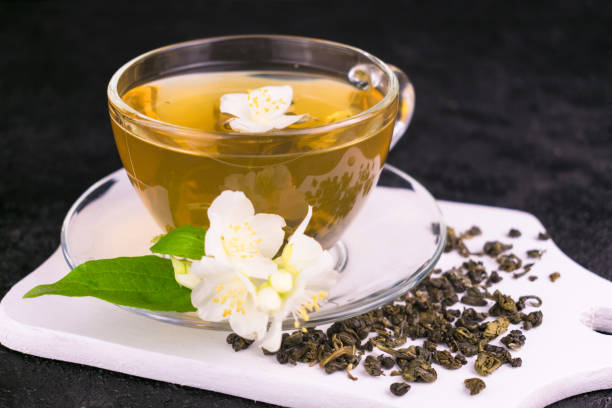 une tasse de thé de jasmin et de fleurs de jasmin sur un fond noir. gros plan. - jasmine tea black tea tea drink photos et images de collection