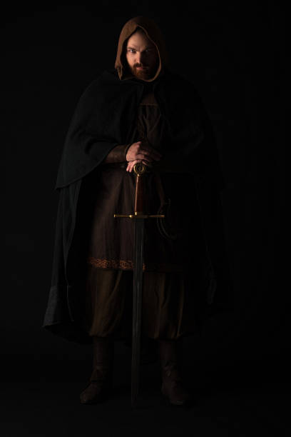 istock medieval Scottish man in mantel with sword in dark isolated on black 1235640054