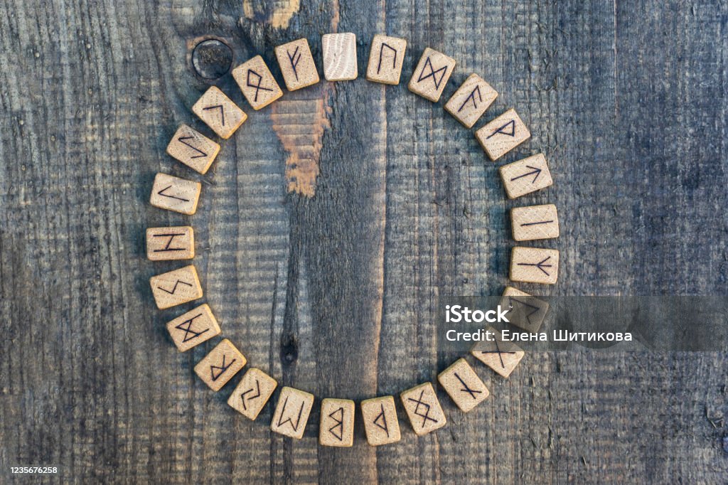 Scandinavian wooden runes on an old wooden table. Elder Futhark. Runes Stock Photo