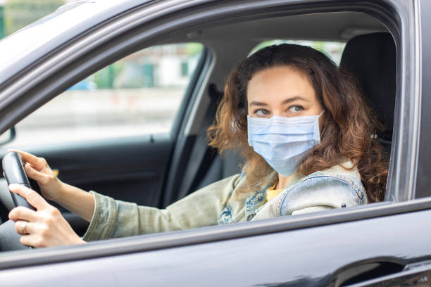 istock Young woman in a mask sitting in a car 1235722201