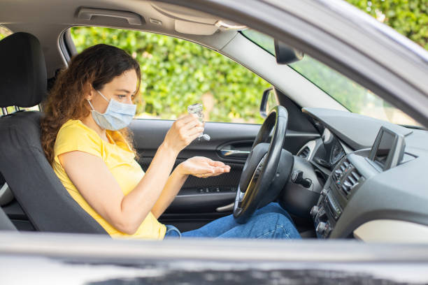 istock Young woman using hand sanitizer in a car 1235723767