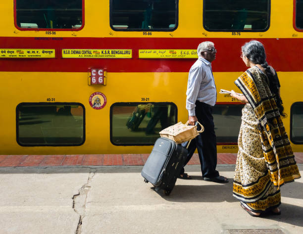 Passengers waiting to board a train Bangalore, Karnataka, India - January 2020: Two Indian passengers wait at the train station to board the double decker express train run by the Indian Railways from Bangalore to Chennai. train air conditioner stock pictures, royalty-free photos & images