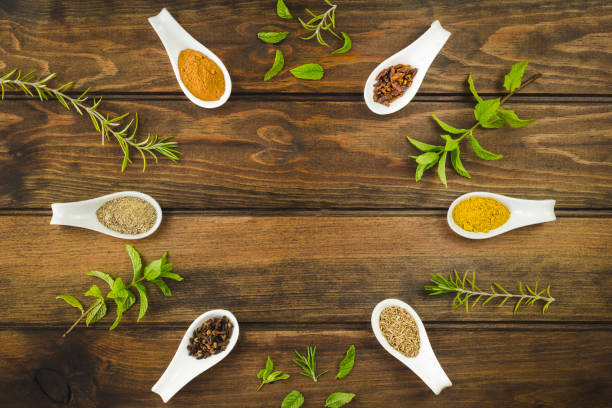 Various colorful herbs and spices on a wooden table. Fresh herbs and spices selection over old wood. Turmeric on dark vintage background with space for text.