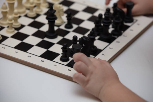 sits at a table and plays chess. The kid concentrated on the game and thinks where to make his next move. Early development, home educational games for children