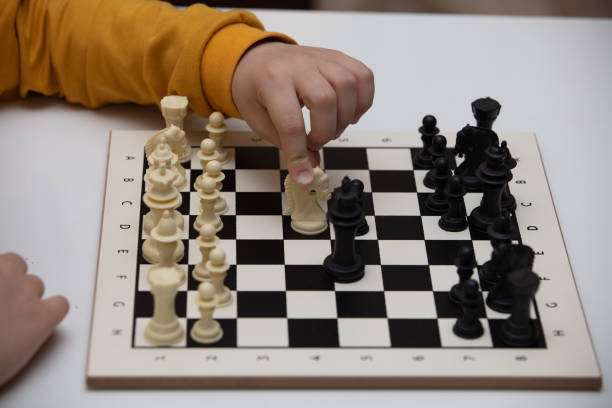 istock sits at a table and plays chess. The kid concentrated on the game and thinks where to make his next move. Early development, home educational games for children 1235786423
