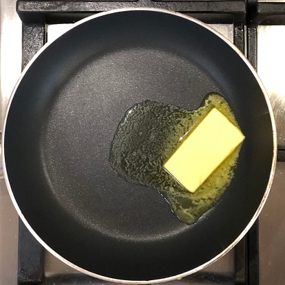 Overhead view of knob of butter melting in frying pan