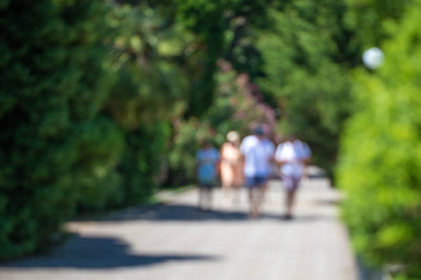 istock Blurred defocused people are walking in the park. 1235842393