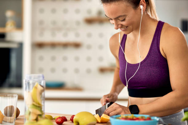 istock Happy sportswoman slicing fruit while preparing smoothie in the kitchen. 1235851191