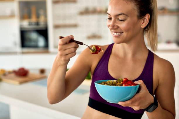 istock Happy athletic woman having fruit salad for a snack in the kitchen. 1235853799