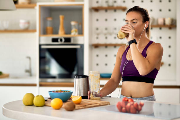 istock Young female athlete drinking fruit smoothie in the kitchen. 1235855864
