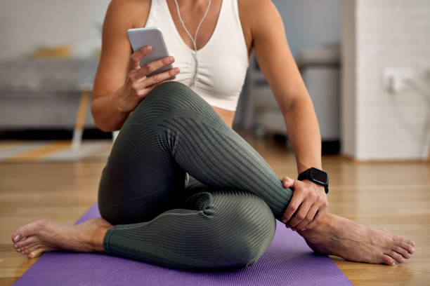 istock Unrecognizable athletic woman using mobile phone while relaxing on the floor. 1235860076