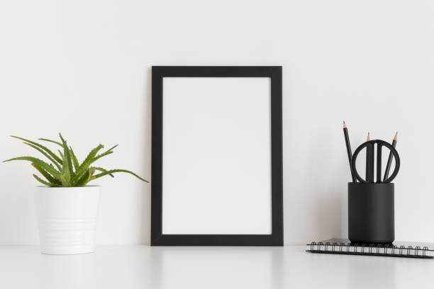 istock Black frame mockup with a succulent plant and workspace accessories on a white table. Portrait orientation. 1235869409