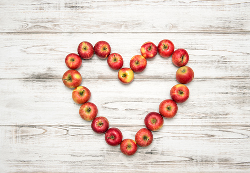 Red apples heart on rustic wooden background. Love concept