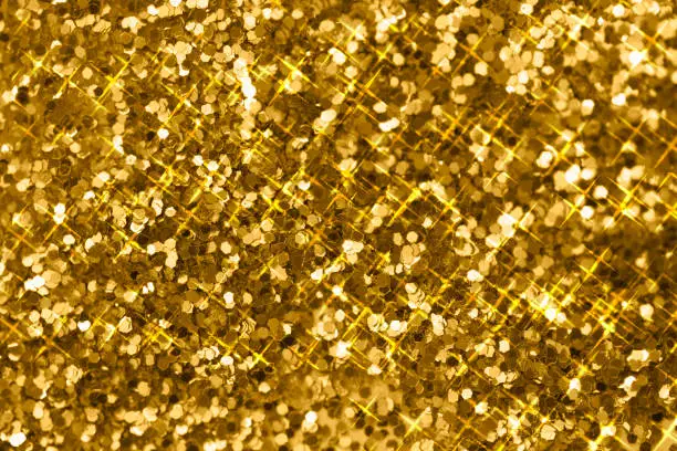 Photo of Pile of shining gold pieces seen from above. Top view macro image of sparkling gold dust for backgrounds and textures